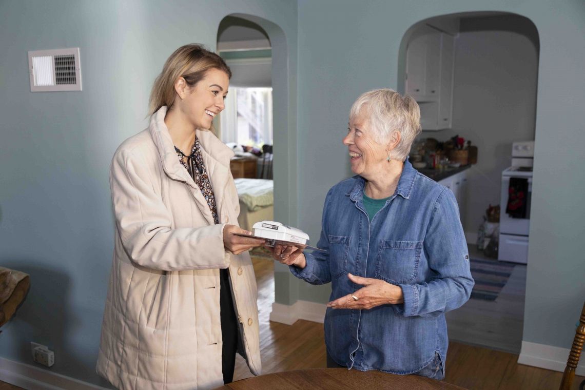 Daughter hands mother carbon monoxide detector